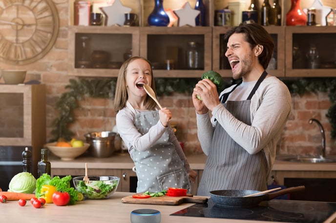 Father-and-daughter-having-fun-while-preparing-lunch-in-kitchen,-singing-1217963715_5387x3591xeva